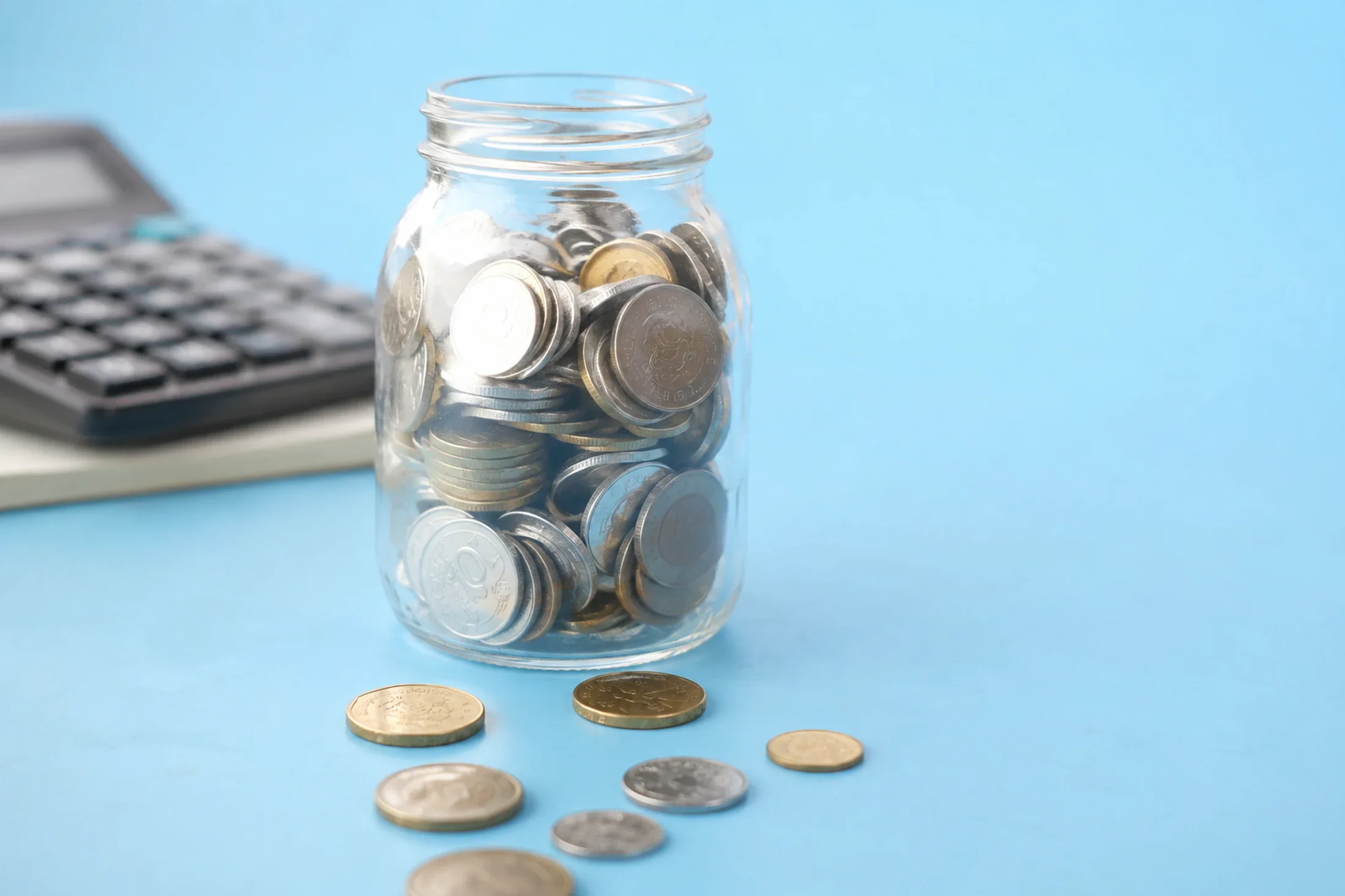 Savings jar beside coins prepared for future expenses